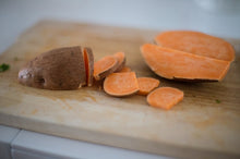 Load image into Gallery viewer, Sliced sweet potatoes on a cutting board
